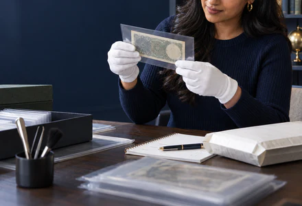 A collector placing a historic British banknote in an archival sleeve